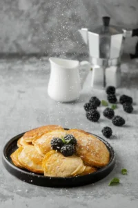 Fluffy pancakes topped with blackberries and a sprinkling of powdered sugar