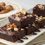 Delicious protein brownies topped with nuts and chocolate.