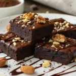 Decadent protein brownies topped with nuts and chocolate drizzle.