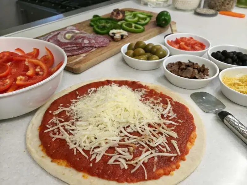 Variety of unique toppings for supreme pizza displayed on a cutting board.